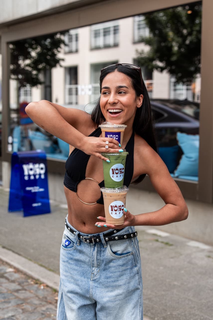 Guest smiling with a stack of iced YOKO Café drinks